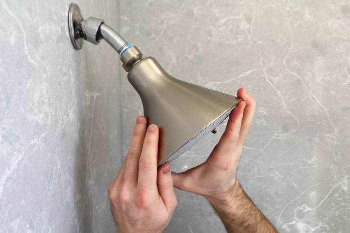 Two hands securing the Canopy Filtered Shower Head onto the shower faucet