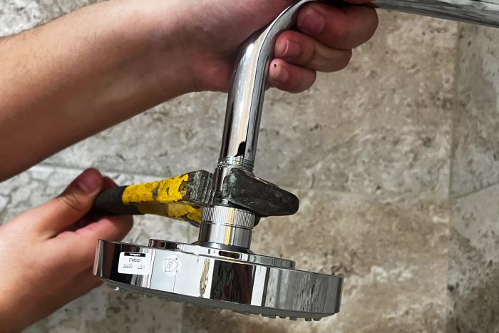 An individual using a tool to install the Hansgrohe Raindance Showerhead