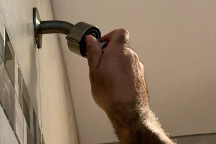 A hand beginning the installation of the Moen Verso Shower with Infiniti Dial