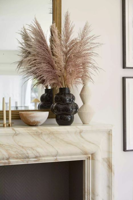 papas grass displayed in a black vase on a mantel