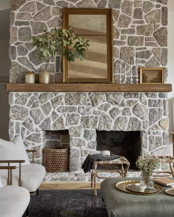 A spacious wooden mantel divided into three sections: vases on the left, a large mirror in the center, and candlesticks paired with a small painting on the right
