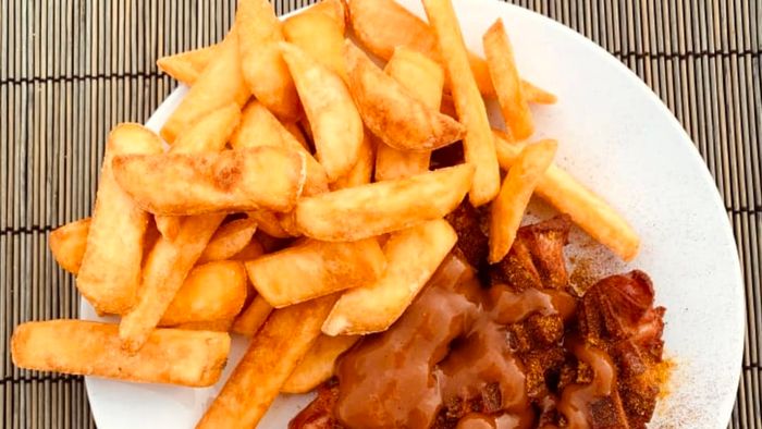 A generous serving of currywurst accompanied by a side of fries.