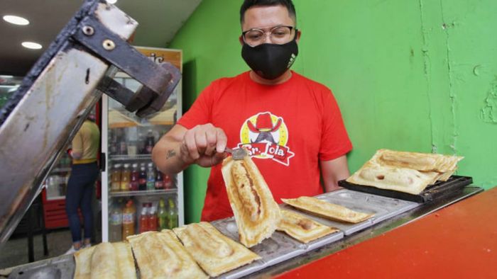 A person preparing a Panchuker hot dog.