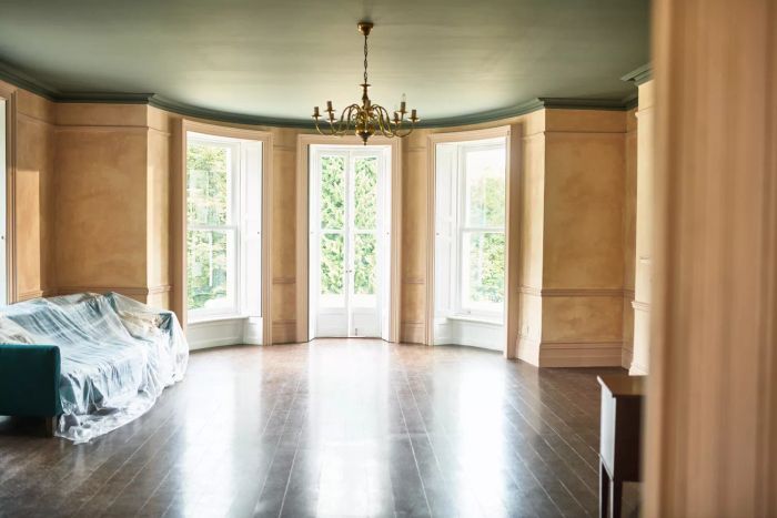 An empty living room featuring crown molding and an antique chandelier