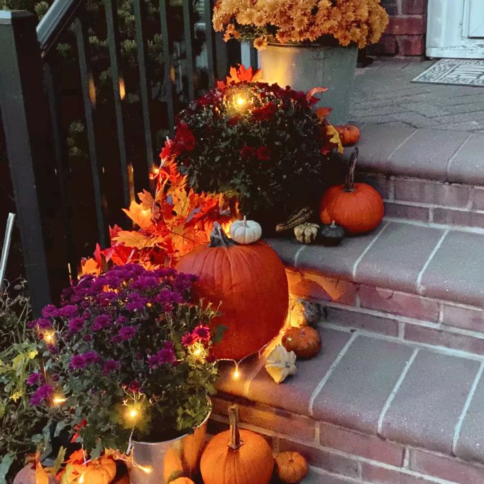 Front porch steps adorned with pumpkins and glowing lights.