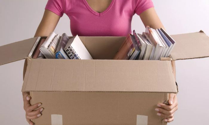 A woman holding a box filled with books