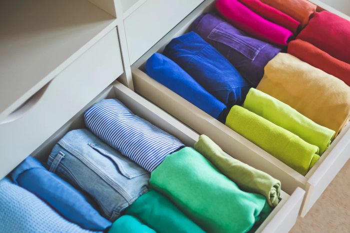 A wardrobe drawer filled with vibrant, neatly arranged clothing, showcasing the idea of efficient storage and spatial organization.