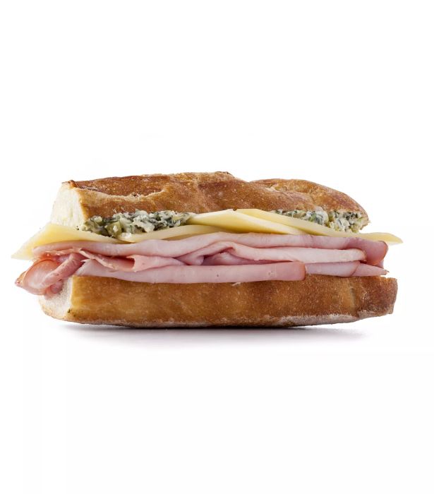 A side view of a French Ham and Cheese Sandwich showcasing layers of ham, Gruyère cheese, and a spread of cornichons, butter, Dijon mustard, and tarragon.