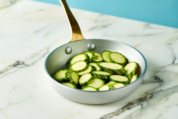 Sliced courgette cooking in a cast iron skillet - stock photo