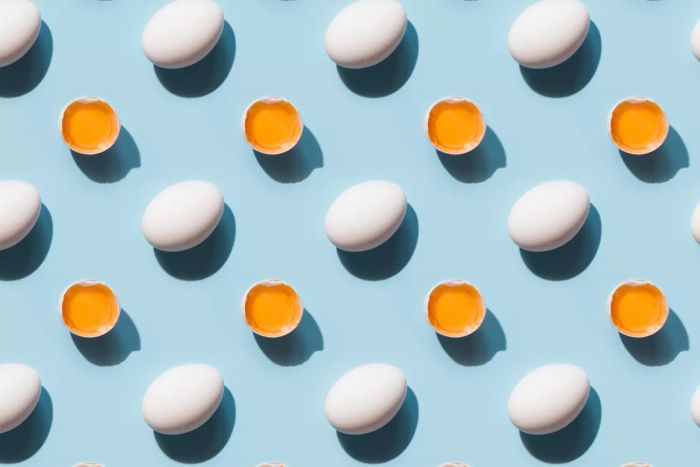 Organic white eggs and yolk with shadow on blue. Abstract seamless pattern