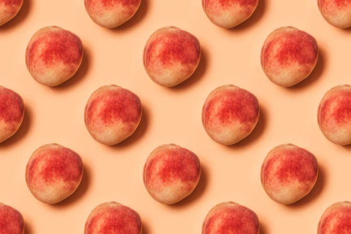 A soft peach skin against a delicate pastel backdrop. Top-down view.
