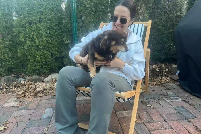 A person and a dog relaxing in the Serena & Lily Teak Sling Chair