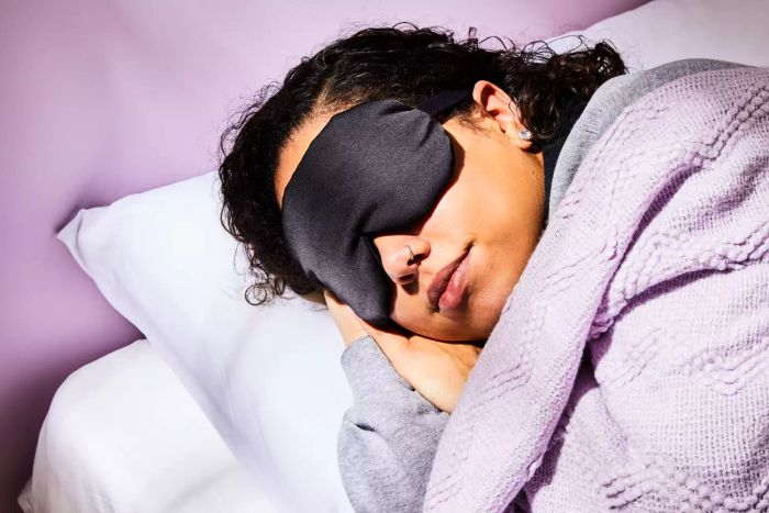 A woman peacefully sleeping while wearing the Alaska Bear Silk Sleep Mask.
