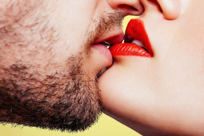 A couple kissing, one person sporting a mustache and beard