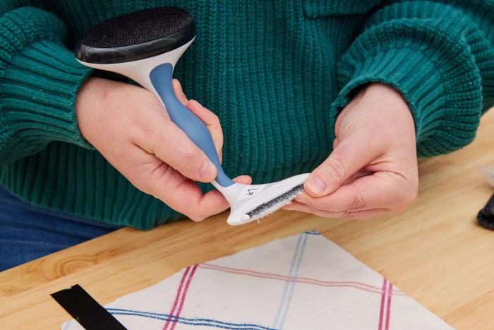 A pair of hands cleaning the Gleener Fabric Shaver & Lint Brush