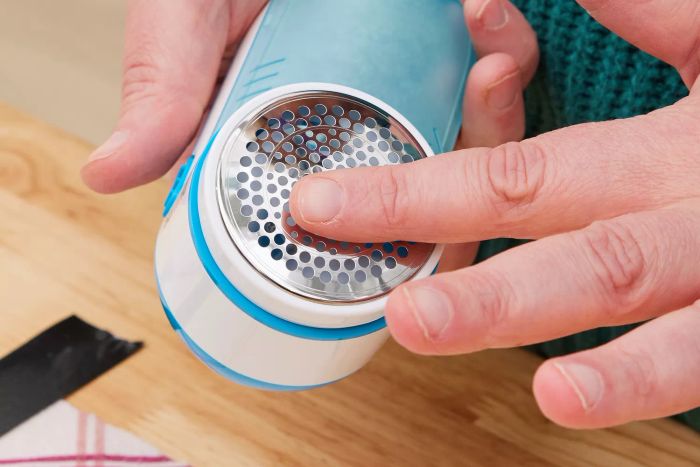 A person running their finger over the Philips GC026 Electric Lint Remover and Fabric Shaver