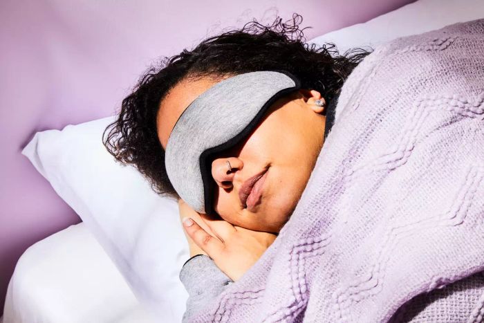 A woman peacefully sleeping with the Ostrichpillow Eye Mask on, enjoying a restful night.
