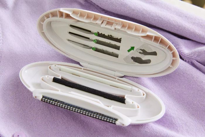 An opened Gleener On The Go Portable Compact Fabric Shaver & Lint Remover displayed against a purple background