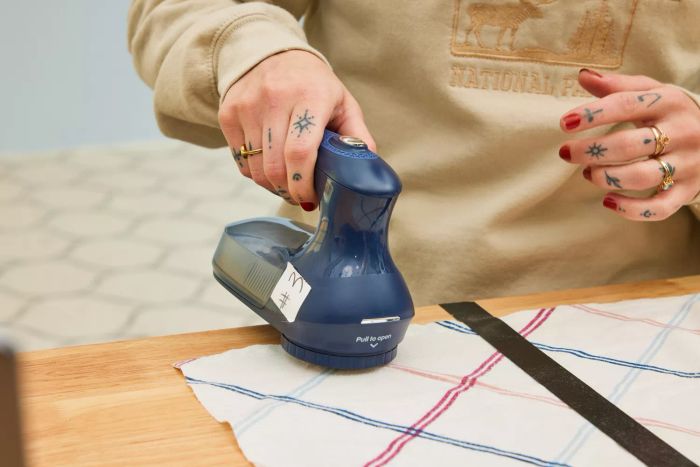 An individual using the Beautural Sweater Fabric Shaver Home-Edition on a vibrant piece of fabric.