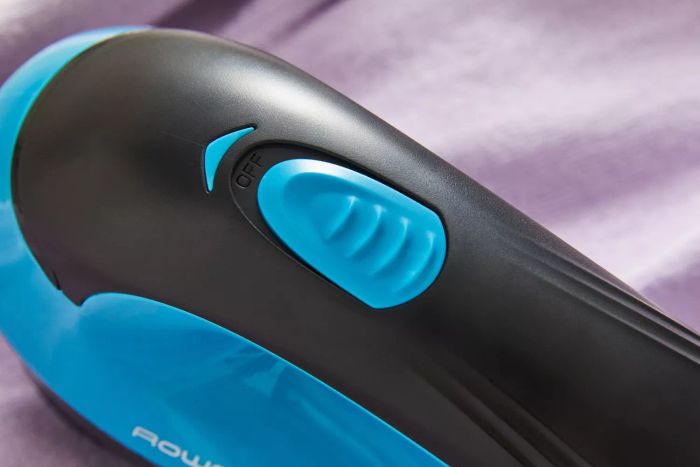 A focused shot highlighting the power switch on the Rowenta Portable Lint Remover Shaver with Adjustable Shave Height.