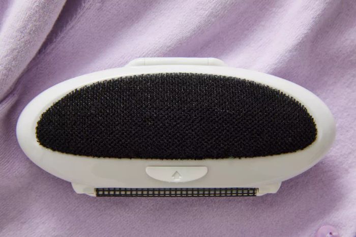 The Gleener On The Go Portable Compact Fabric Shaver & Lint Remover displayed on a purple background
