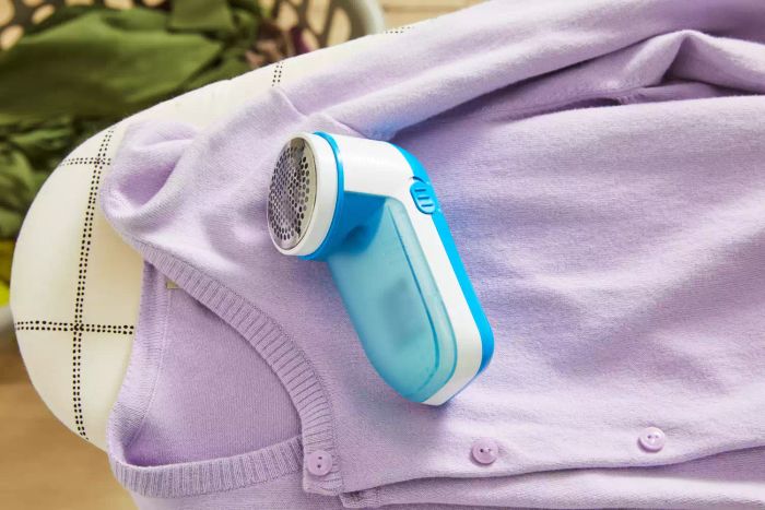 The Philips GC026 Electric Lint Remover and Fabric Shaver in use on a purple cardigan
