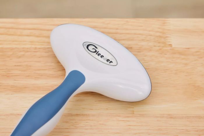 A detailed close-up of the logo on the Gleener Fabric Shaver & Lint Brush placed on a wooden floor