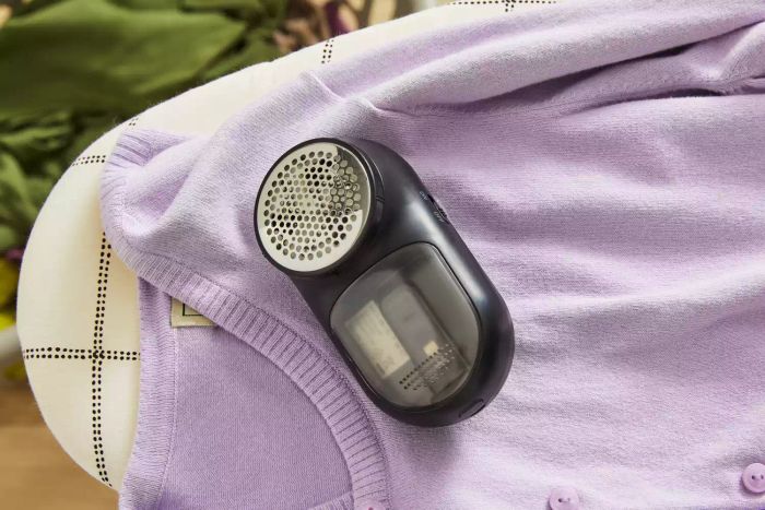 Magitec Fabric Shaver placed on a purple sweater resting on an ironing board