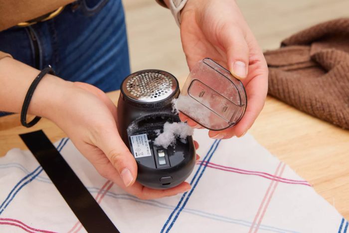 A person removing shavings from the Magictec Rechargeable Fabric Shaver