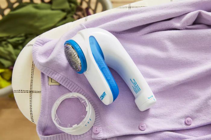 The Conair Fabric Shaver and Lint Remover in use on a purple sweater