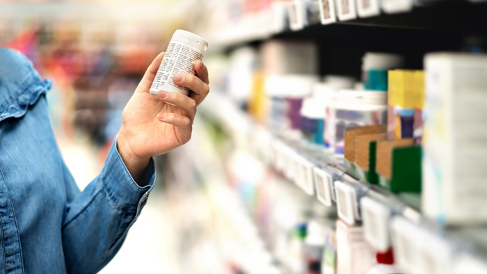 A customer in a pharmacy holding a bottle of medicine.