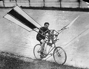 A man pedals a bicycle fitted with wings on its frame.