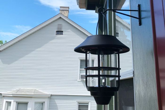 Derynome Solar Lantern Outdoor Lights with Wall Mount Kit hanging from a hook outside