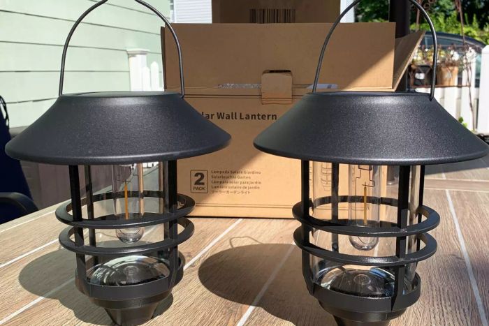 Derynome Solar Lantern Outdoor Lights with Wall Mount Kit placed atop a table outdoors with its original packaging