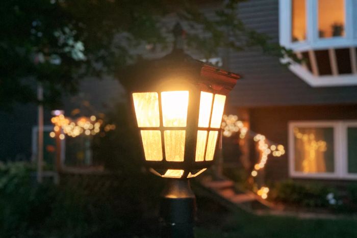 Kemeco Solar Post Light positioned outdoors in front of a house during the night, showcasing its glow.