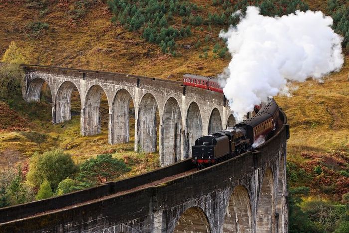 The Jacobite Express crosses a curved viaduct in Glenfinnan, Scotland.