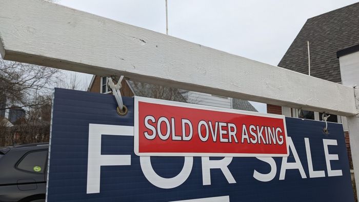 House with a 'For Sale' sign in front