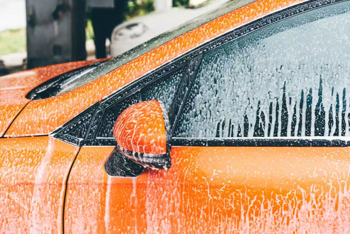 Using a high-pressure washer at a self-serve car wash.