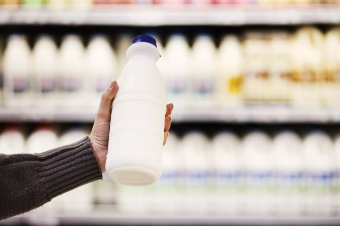 A person holding a bottle of milk in a grocery store