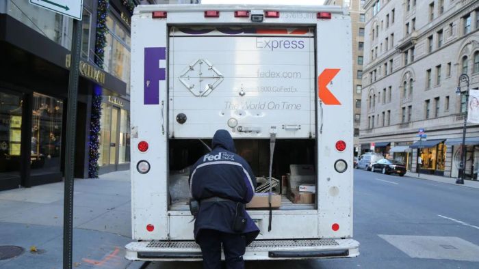 A FedEx employee unloading parcels from a delivery vehicle