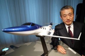 Takeo Fukui, President and Representative Director of Honda Motor Co., Ltd., poses next to a HondaJet model during a media conference on December 17, 2003, in Tokyo, Japan.