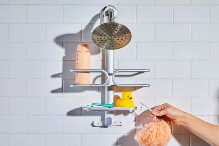 An individual placing a loofah onto the OXO 3-Tier Shower Caddy