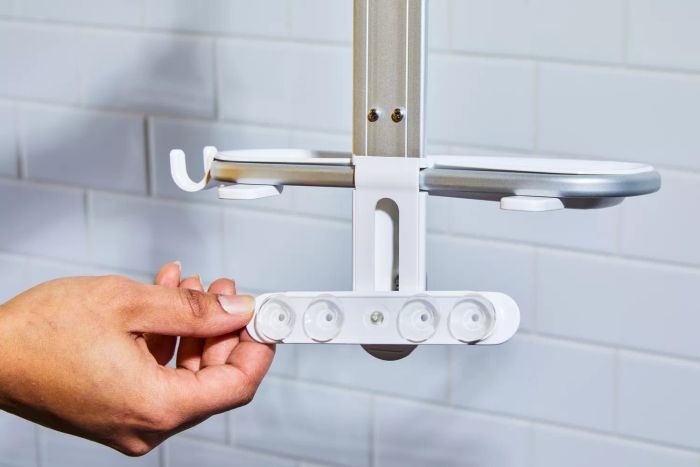 An individual holding a component of the OXO 3-Tier Shower Caddy
