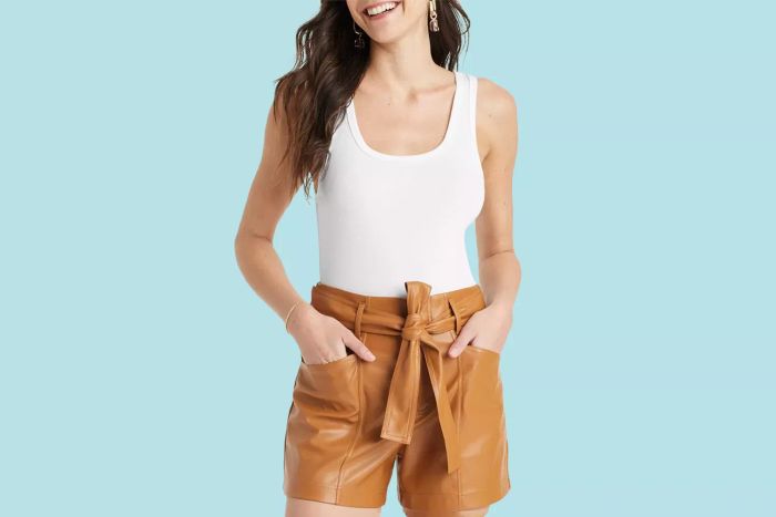 A person models the white tank top from Target, which we highly recommend, set against a vibrant blue background.