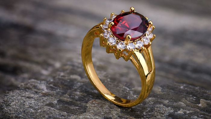 A ring featuring a prominent red gemstone accented by smaller white crystals