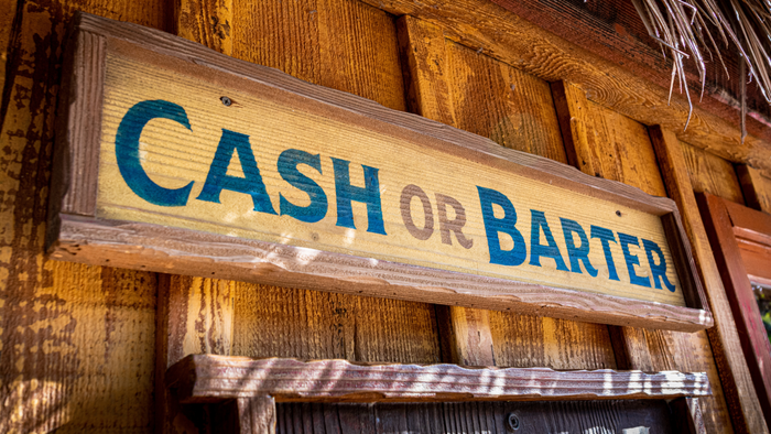 An old-fashioned wooden sign with the words 'cash or barter' written on it