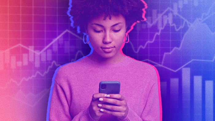A woman checking her phone with a stock market display in the background