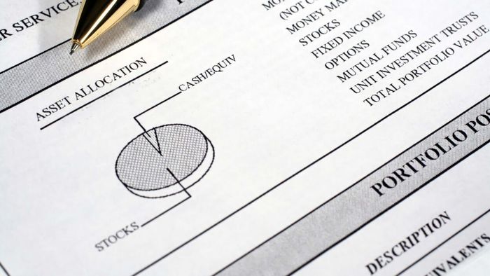 A printed investment portfolio summary displayed in a photo
