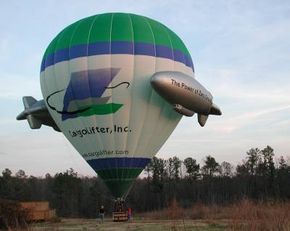 A hot air balloon in shades of blue, green, and white rests on the ground, getting ready to take off.