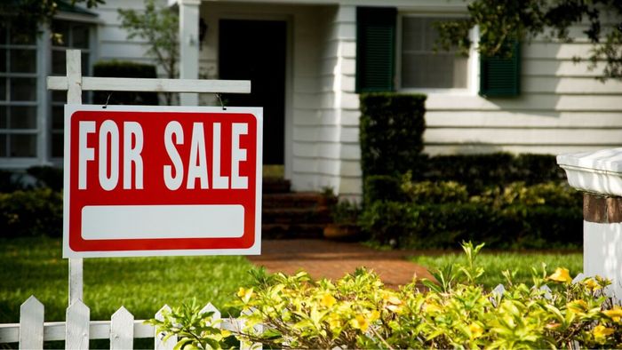 A small house displaying a for sale sign